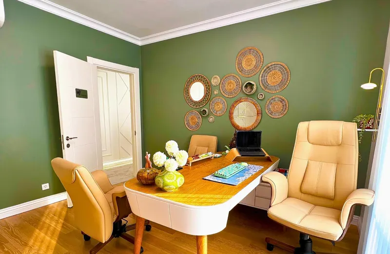 Consultation room with a desk and a green wall of woven mirrors