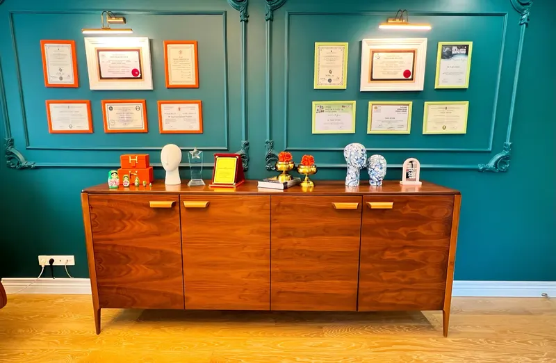 Framed diplomas and certificates above a walnut cabinet in Dr. Yilmaz's office