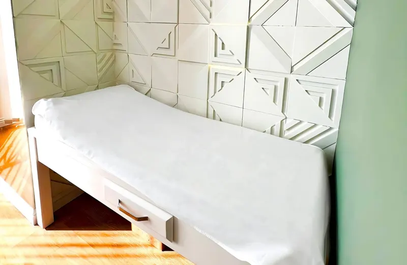 Examination couch against a white sculpted wall in a consultation room